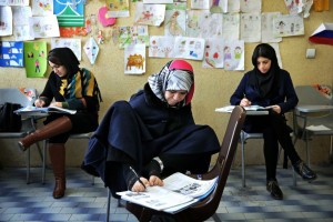 In this picture taken on Wednesday, March 11, 2015, Zohreh Etezadossaltaneh, center, who was born without arms, writes with her feet during an English language class, in Tehran, Iran. Now 52 years old, the retired Iranian teacher has dedicated herself to helping others with similar disabilities live full and satisfying lives. (AP Photo/Ebrahim Noroozi)
