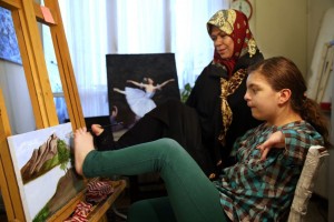 In this picture taken on Wednesday, Jan. 21, 2015, Zohreh Etezadossaltaneh, who was born without arms, teaches painting to 12-year old Sara Sahraei, who is disabled, at her home, in Tehran, Iran. Now 52 years old, the retired Iranian teacher who was born without arms has dedicated herself to helping others with similar disabilities live full and satisfying lives.(AP Photo/Ebrahim Noroozi)