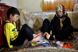In this picture taken on Jan. 21, 2015, Zohreh Etezadossaltaneh, right, who was born without arms, teaches 9-year old Afghan boy Roohollah Jafar, how to use his feet during a lesson at her home, in Tehran, Iran. Now 52 years old, the retired Iranian teacher has dedicated herself to helping others with similar disabilities live full and satisfying lives. (AP Photo/Ebrahim Noroozi)