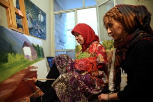 In this picture taken on Wednesday, Jan. 28, 2015, Zohreh Etezadossaltaneh, left, who was born without arms, paints as her teacher Parisa Samavatian observes, at her home in Tehran, Iran. "She works so easily that I've totally forgotten she paints with her feet, said Samavatian.(AP Photo/Ebrahim Noroozi)