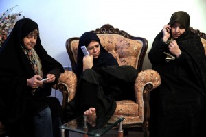 In this picture taken on Saturday, Jan. 31, 2015, Zohreh Etezadossaltaneh, center, talks on her mobile phone, held with her foot, during a meeting at her friend's home in Tehran, Iran. Now 52 years old, the retired Iranian teacher who was born without arms has dedicated herself to helping others with similar disabilities live full and satisfying lives.(AP Photo/Ebrahim Noroozi)