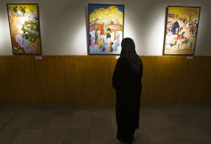 A visitor looks at paintings by Zohre Etezadolsaltaneh at an exhibition in Tehran January 23, 2011. Etezadolsaltaneh,49, a retired special education teacher, was born with no arms but lives the life of an independent woman who has been doing cooking, painting, weaving kilims and taking care for her mother who is a cancer patient. She gets $600 per month as pension from the government and lives by the mantra "To want is to succeed". Picture taken January 23, 2011. REUTERS/Raheb Homavandi  (IRAN - Tags: SOCIETY)